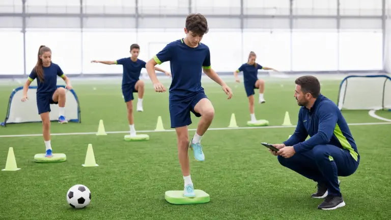 Denge ölçümü protokolünün doğru ve güvenli uygulaması yapan çocuklar ve uygulamayı izleyen spor bilimci.