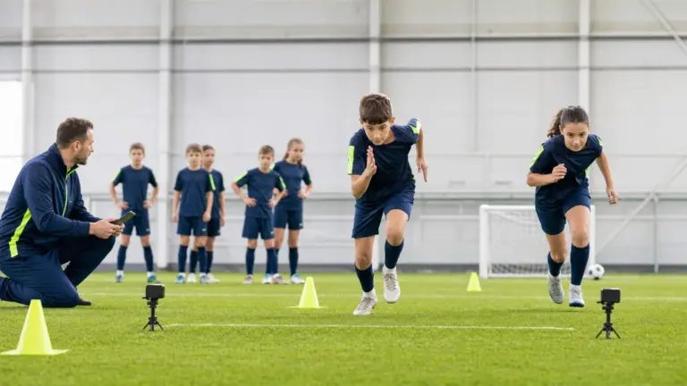 20 metre sürat testi protokolünün doğru ve güvenli uygulaması yapan çocuklar ve uygulamayı izleyen spor bilimci.